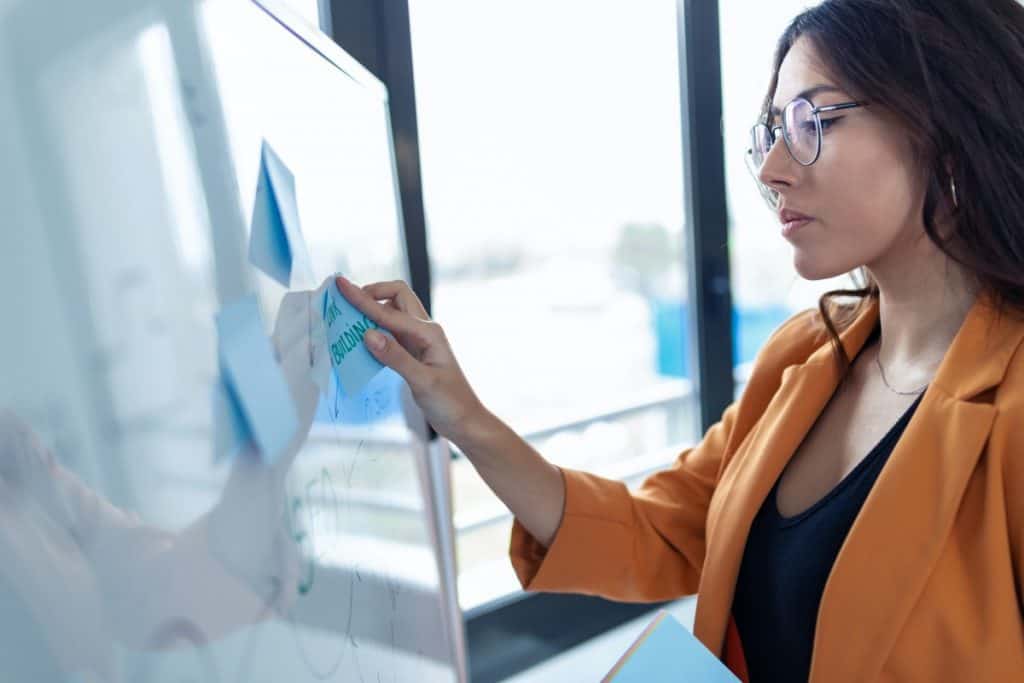 Business young woman working on white board with post it stickers in the office.