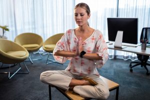 Businesswoman doing yoga with hands tied