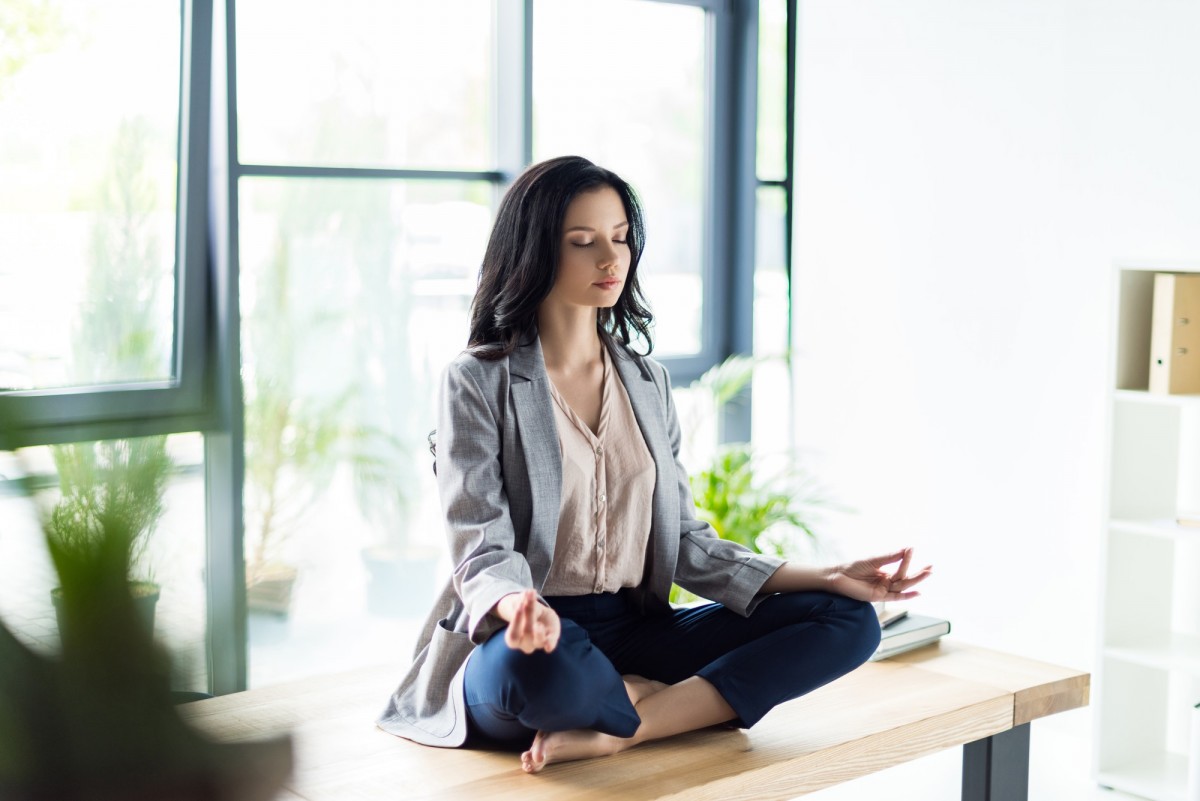 relaxed businesswoman with eyes closed meditating at workplace in office