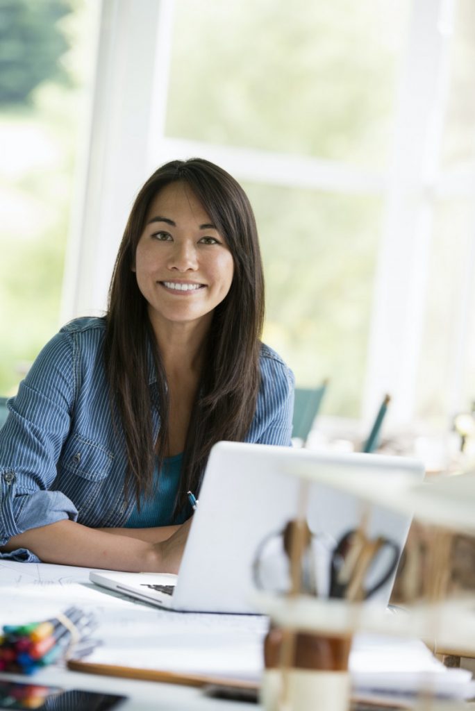 A woman in an office, working at a laptop computer.