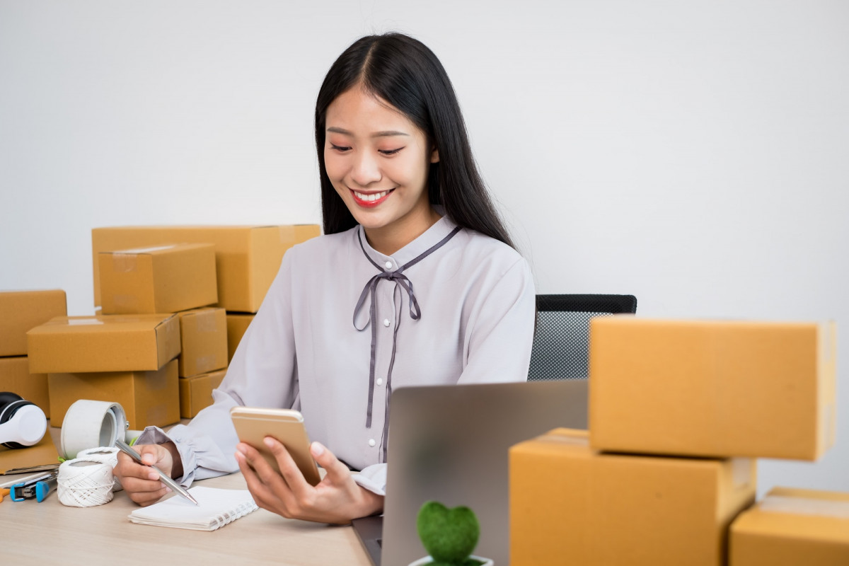 Young Asian woman business owner with many parcel boxes on the table happy online sales job, use you Young Asian woman business owner with many parcel boxes on the table happy online sales job, use you