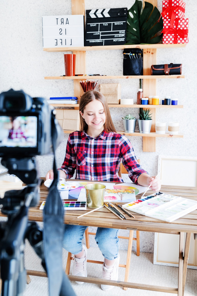 Smiling young woman drawing and recording video for her blog, teaching online, enjoying her hobby Smiling young woman drawing and recording video for her blog, teaching online, enjoying her hobby