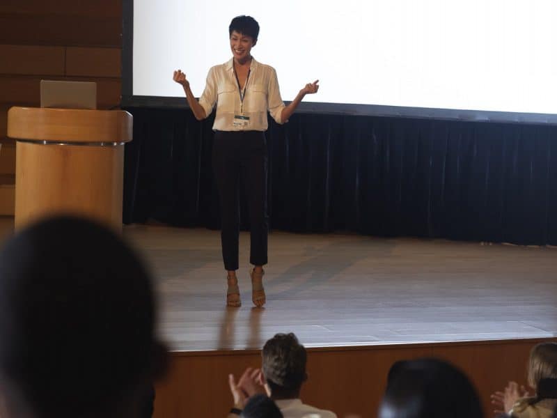 Beautiful businesswoman standing and giving presentation in front of the audience in auditorium